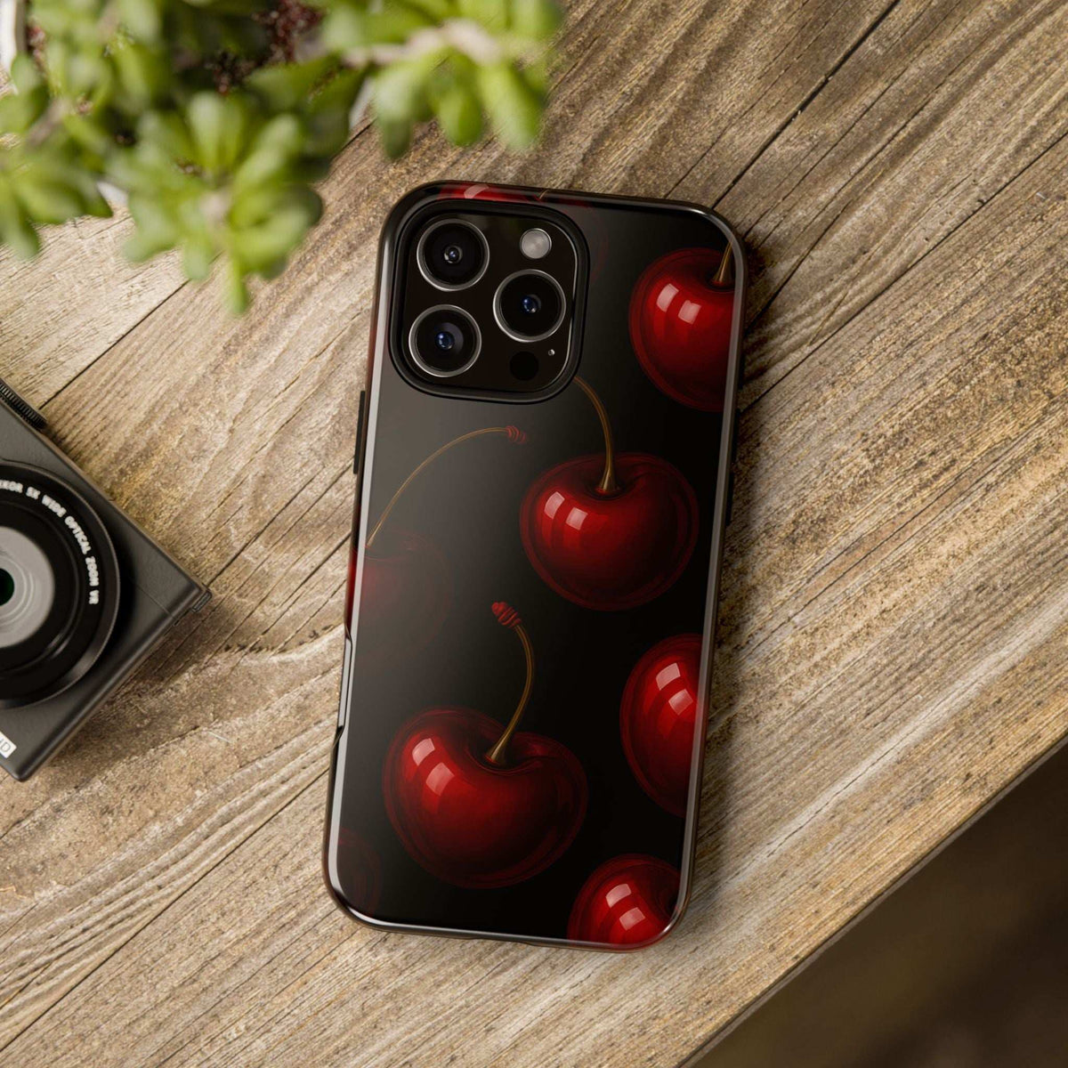 Glossy cherry phone case on wooden surface, black with red cherry pattern