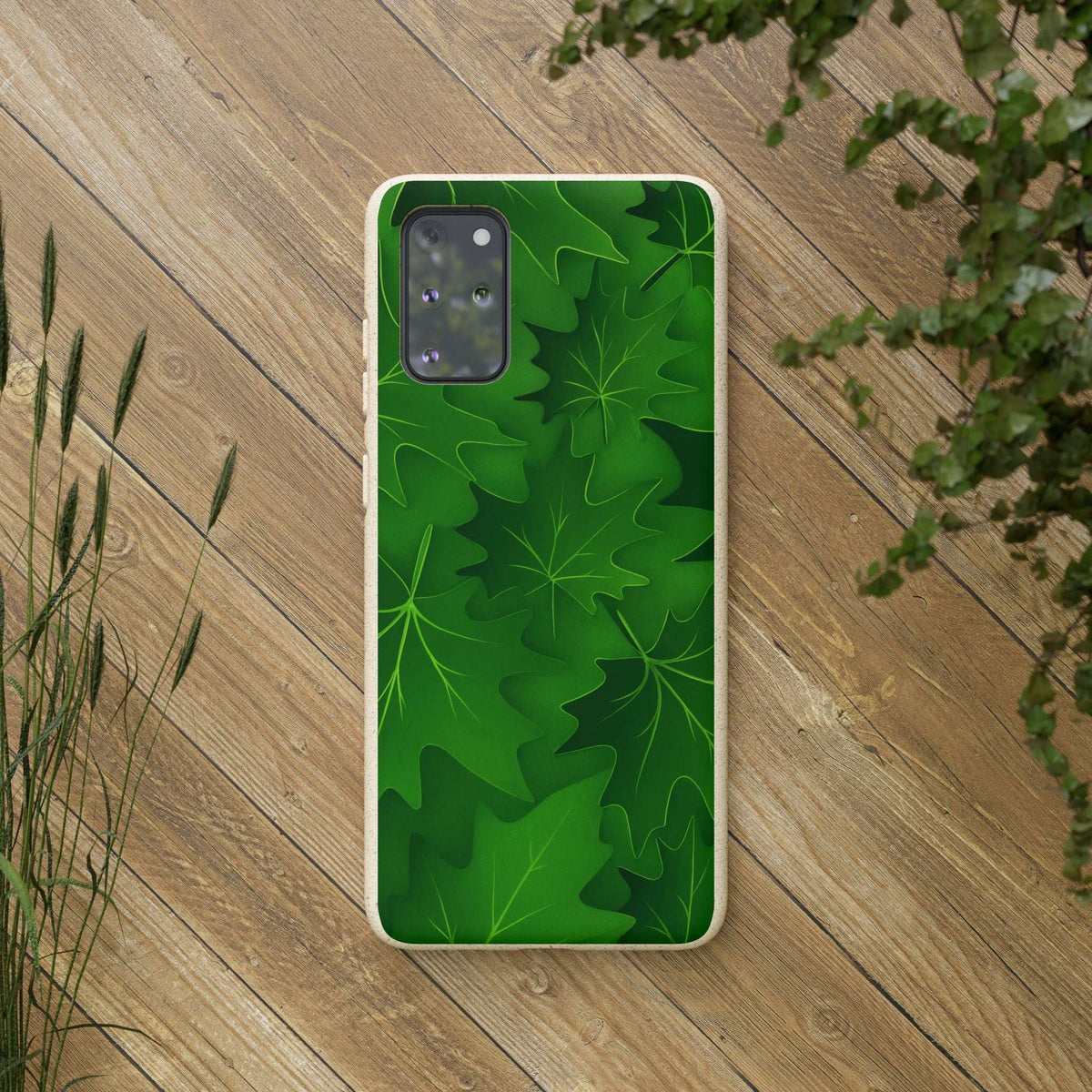 Green botanical leaf phone case with beige speckled edges, back view on wood