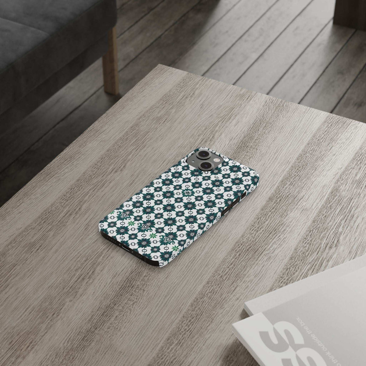 Teal floral geometric phone case on light wood table with rear camera opening visible