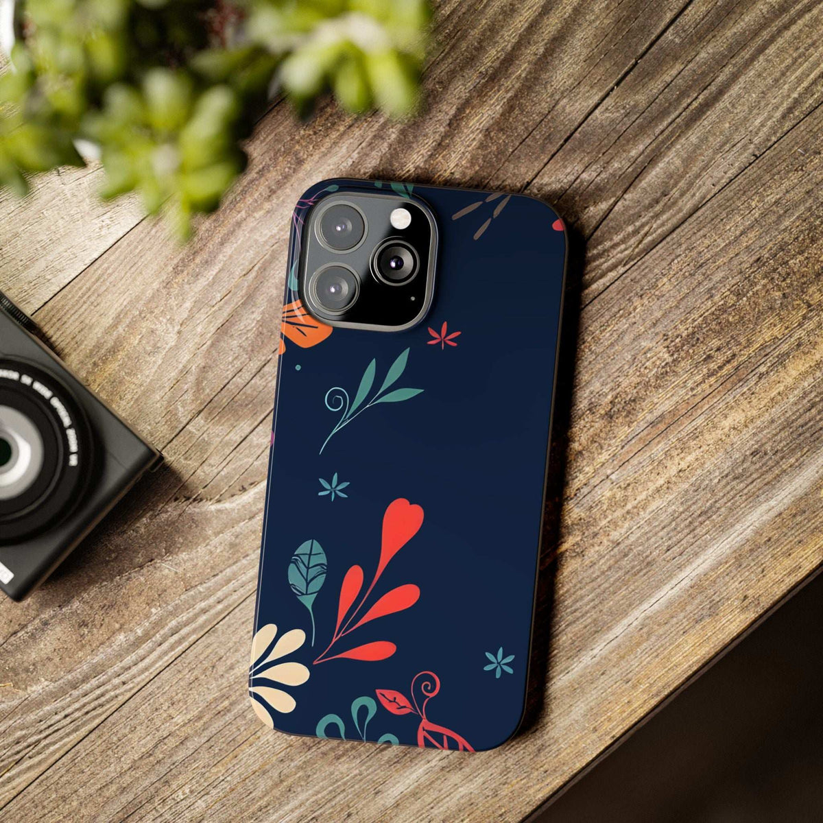 Dark navy floral phone case with red heart, leaf clusters, and teal sprig details