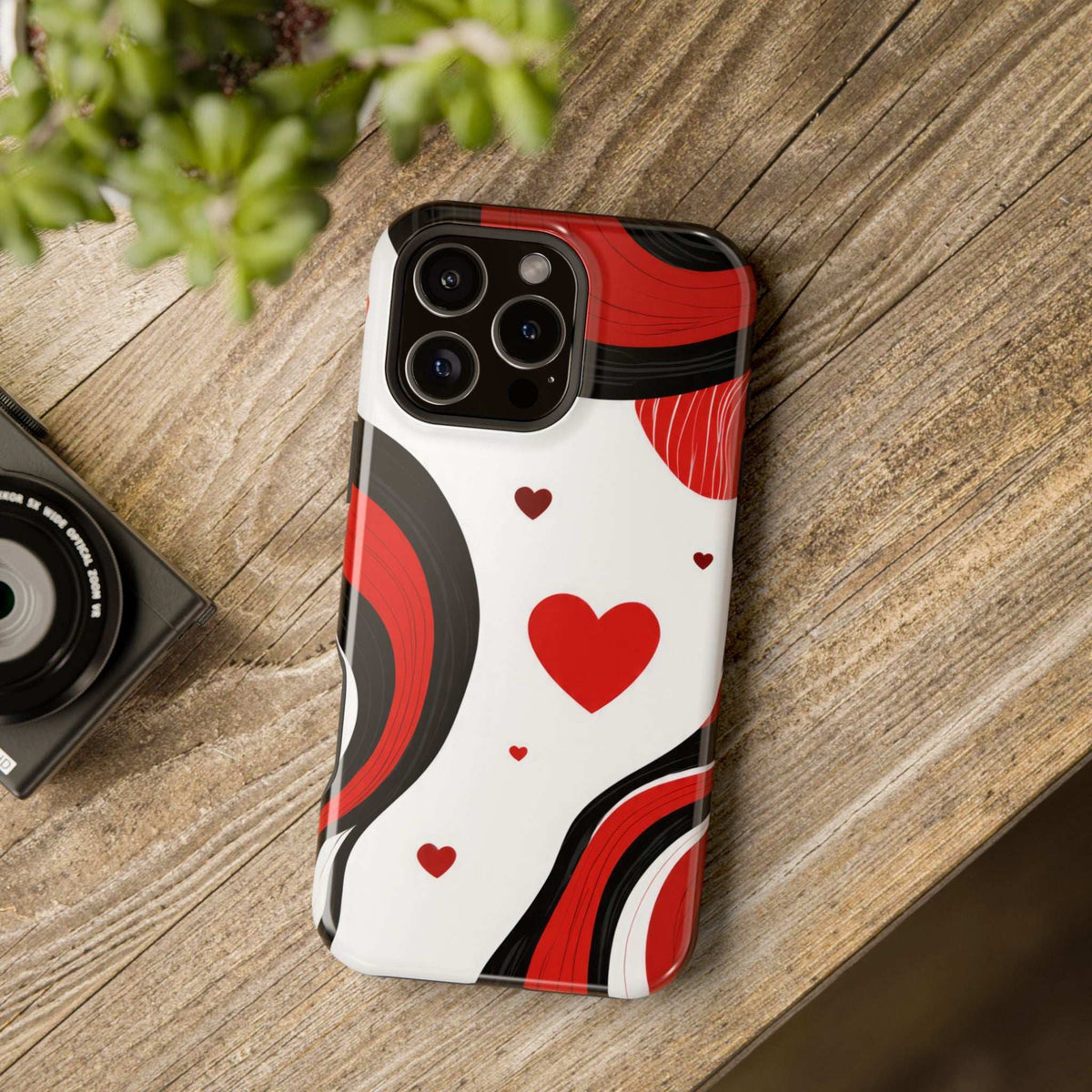 Heart-pattern phone case standing on wood, red hearts on white with black swirls