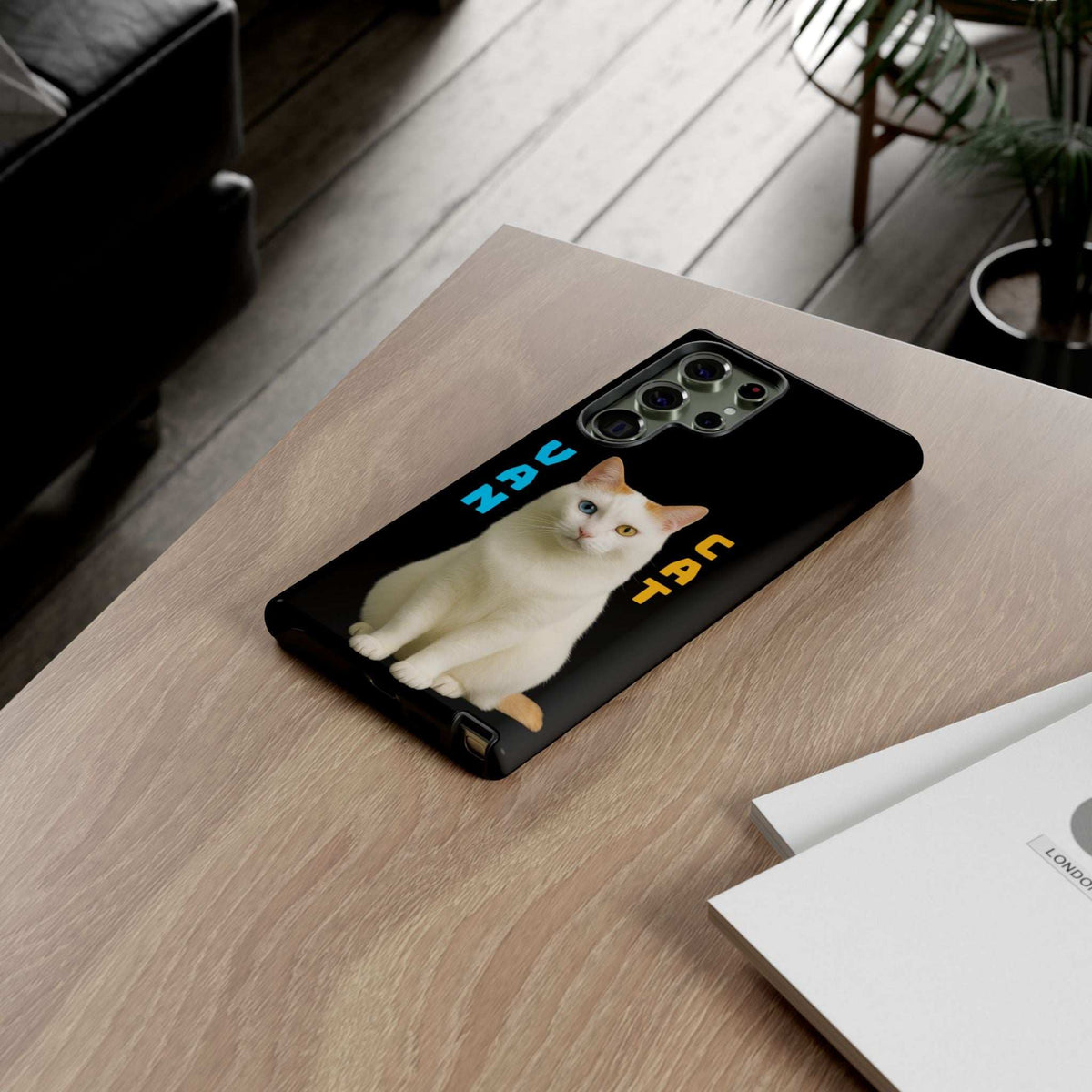 Black phone case with cream cat graphic on a tabletop, showing camera openings