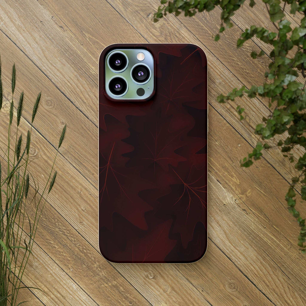 Burgundy leaf-pattern phone case with quad-camera cutout and smooth back.
