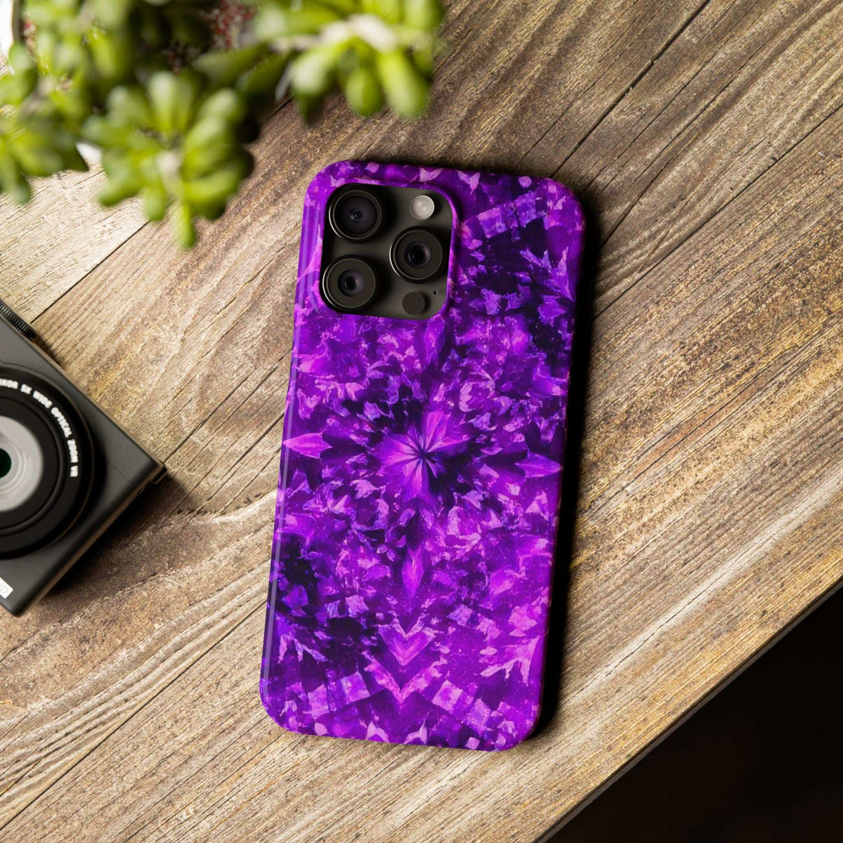 Purple kaleidoscope phone case with triple camera cutouts, glossy purple pattern on wood.