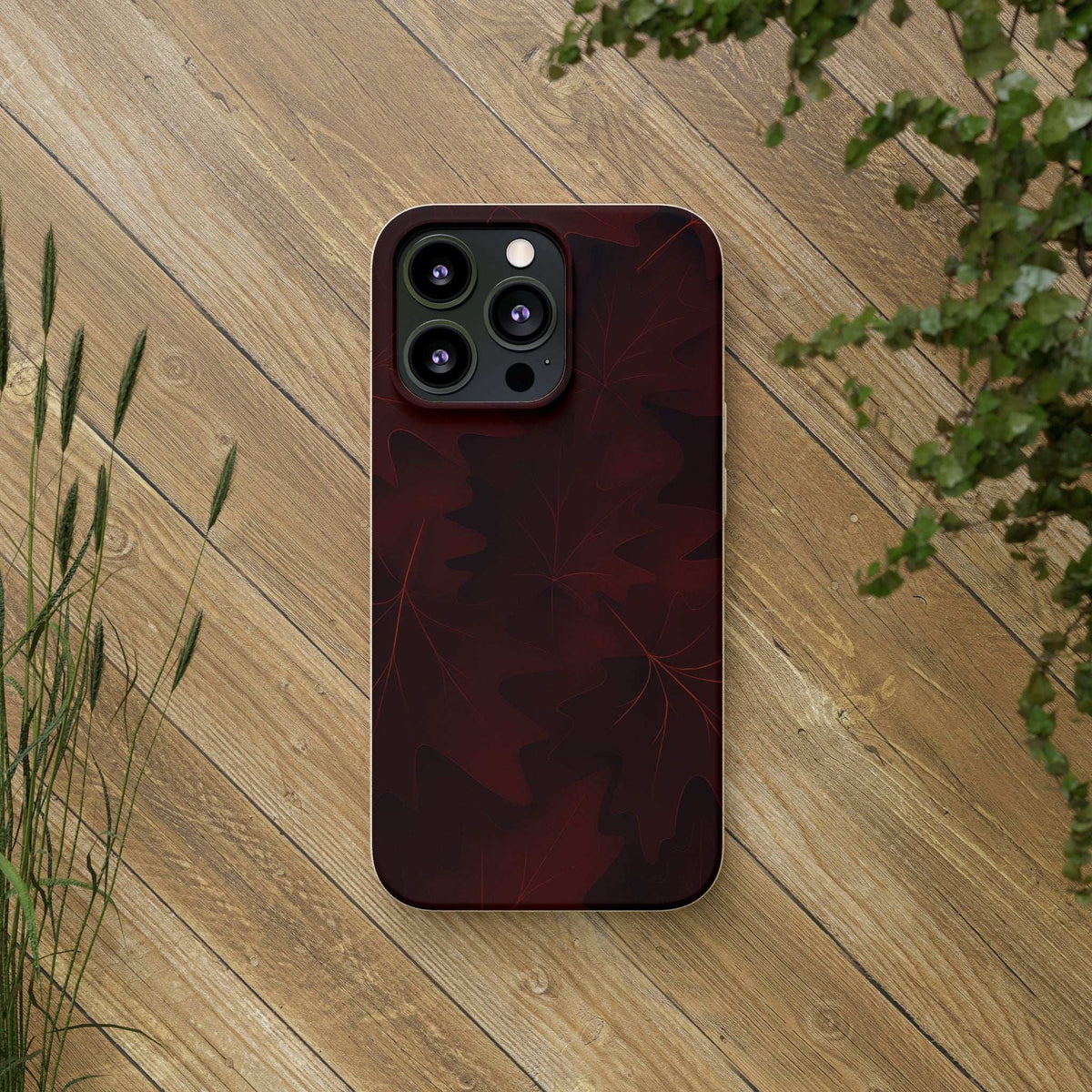 Burgundy leaf-pattern phone case with quad-camera cutout on a flat surface.