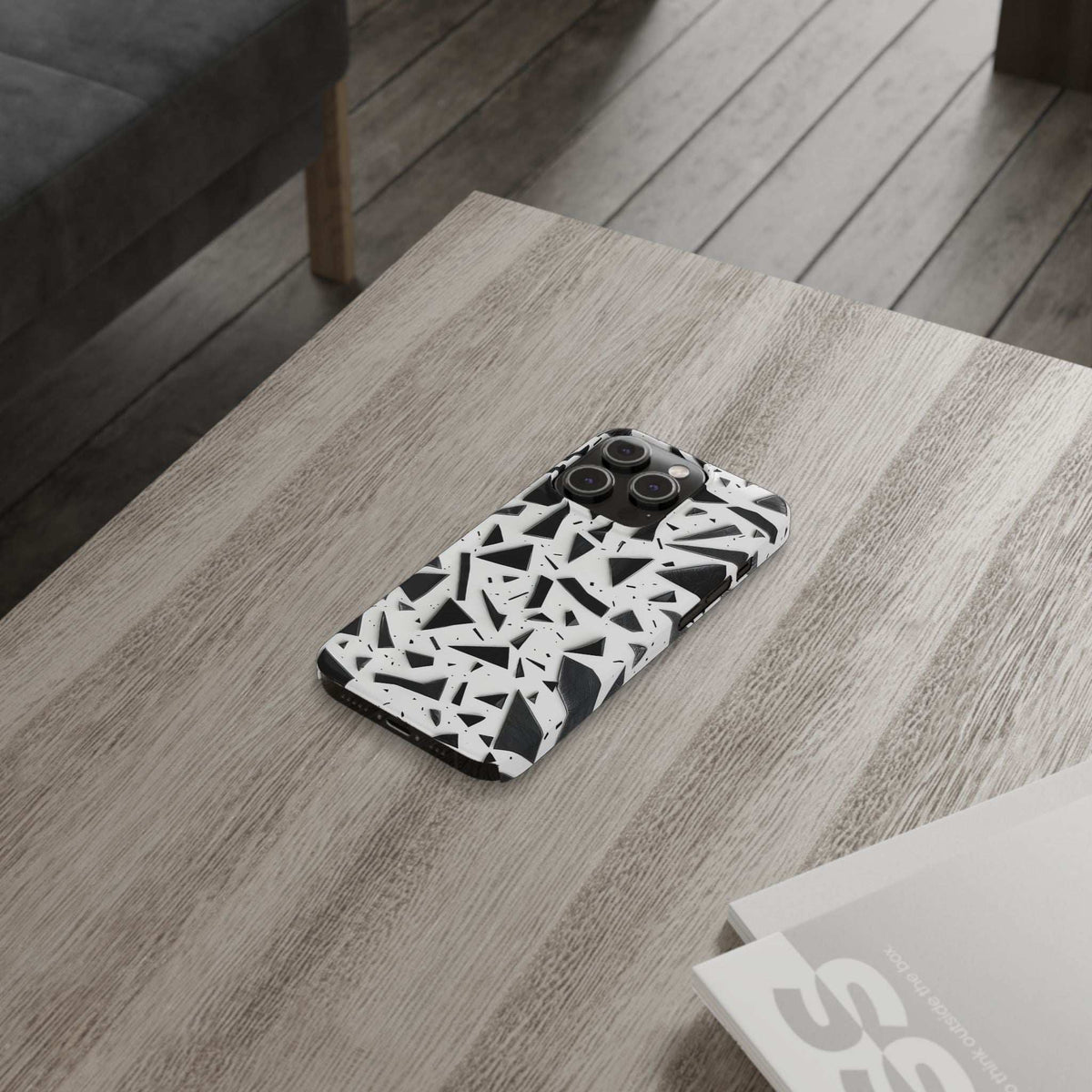 Slim iPhone phone case angled on surface, white abstract black geometric design, camera openings.