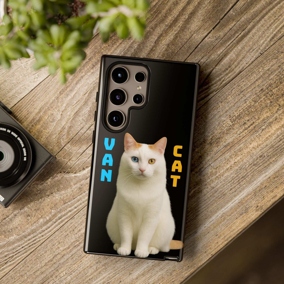 Black phone case with cream cat graphic on a wood surface, camera openings visible
