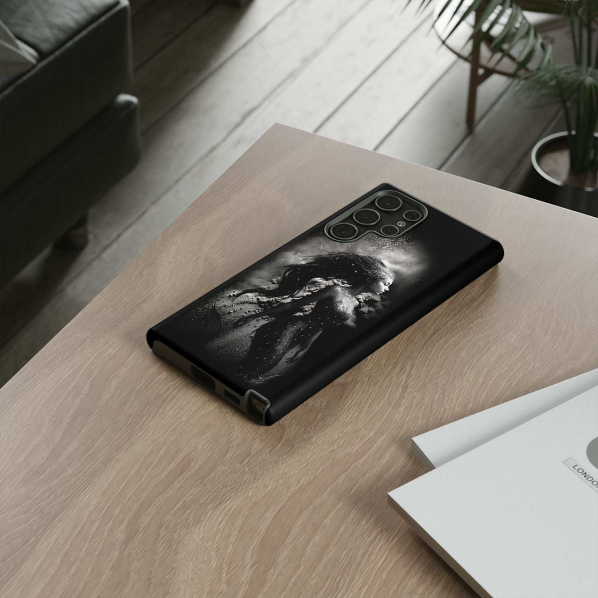 Black phone case with grayscale mermaid illustration and camera cutout, protective edges.