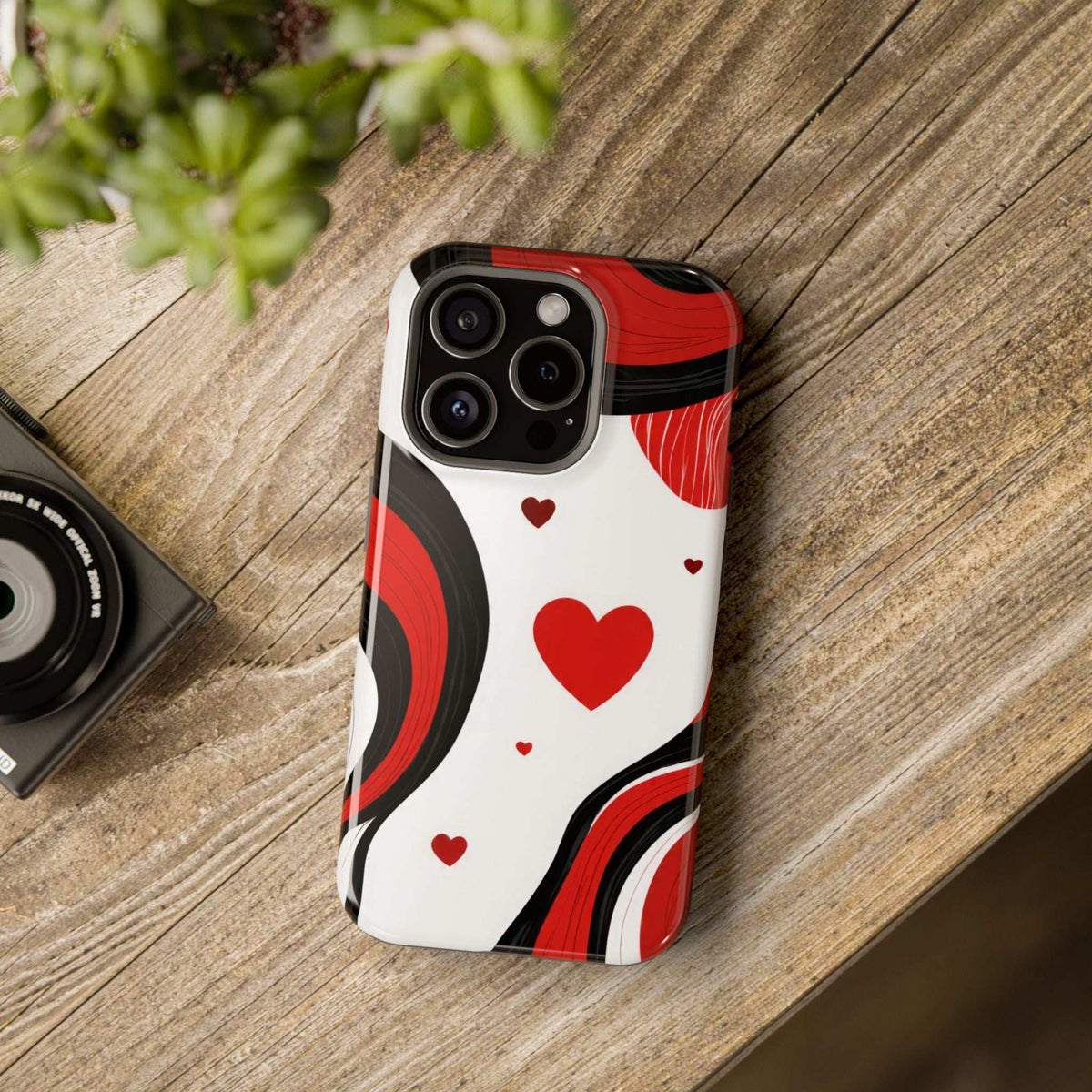 Glossy phone case back on wood: red heart and swirl design in white with red and black waves.