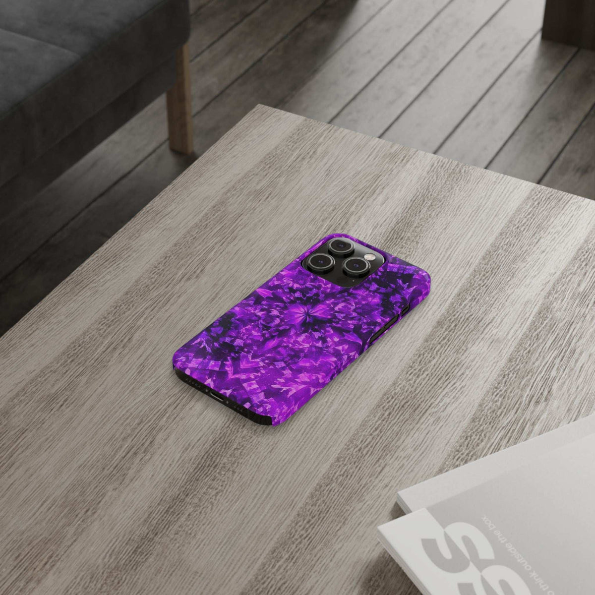 Purple kaleidoscope iPhone case on wood floor, camera lens openings shown