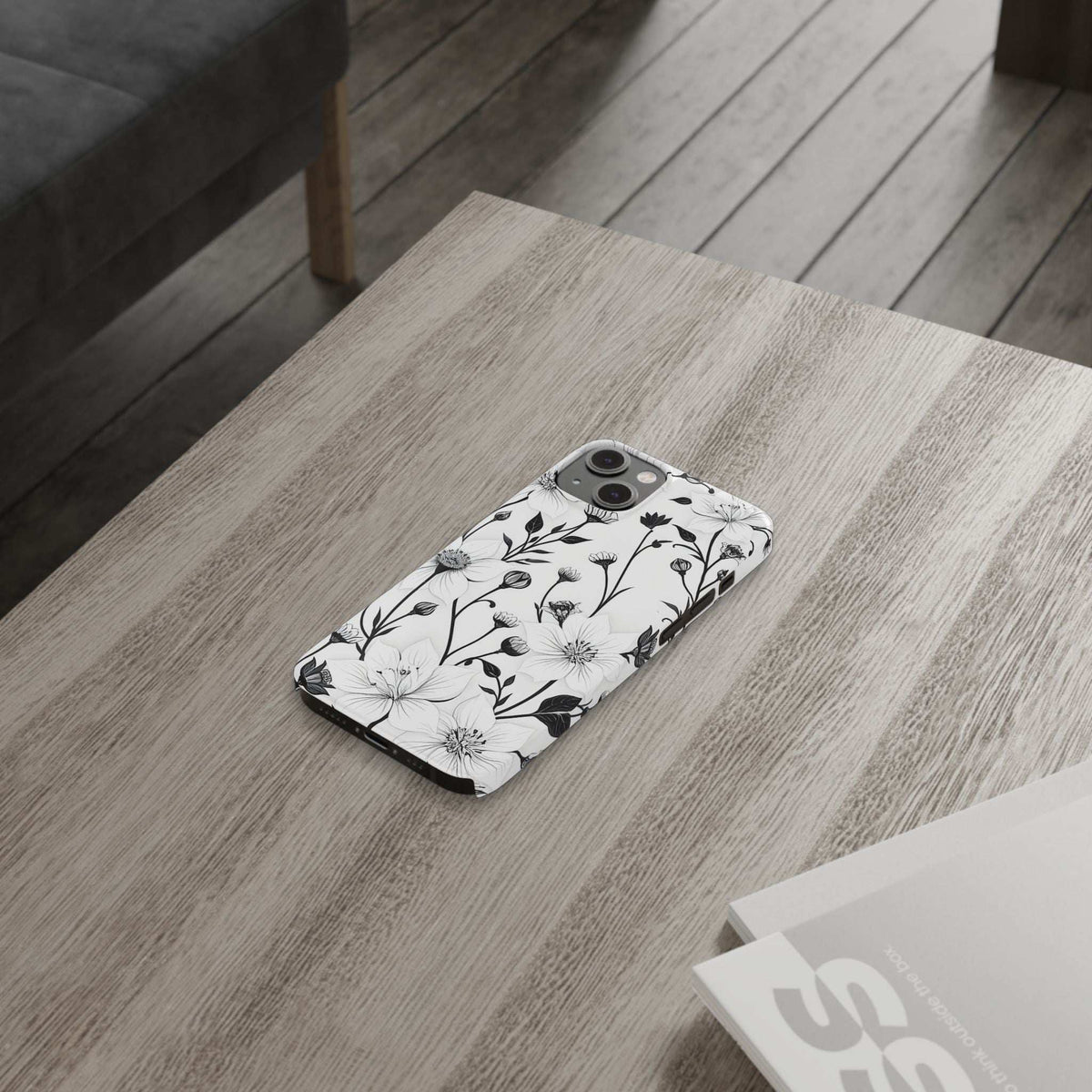 Monochrome floral phone case shown on a surface with white flowers and black stems.