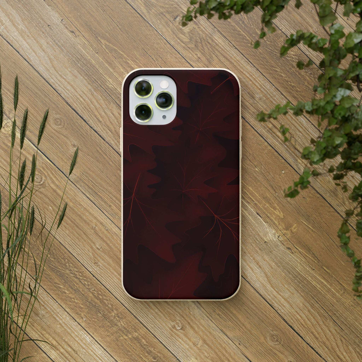 Maroon leaf-pattern phone case on phone with quad-camera cutout
