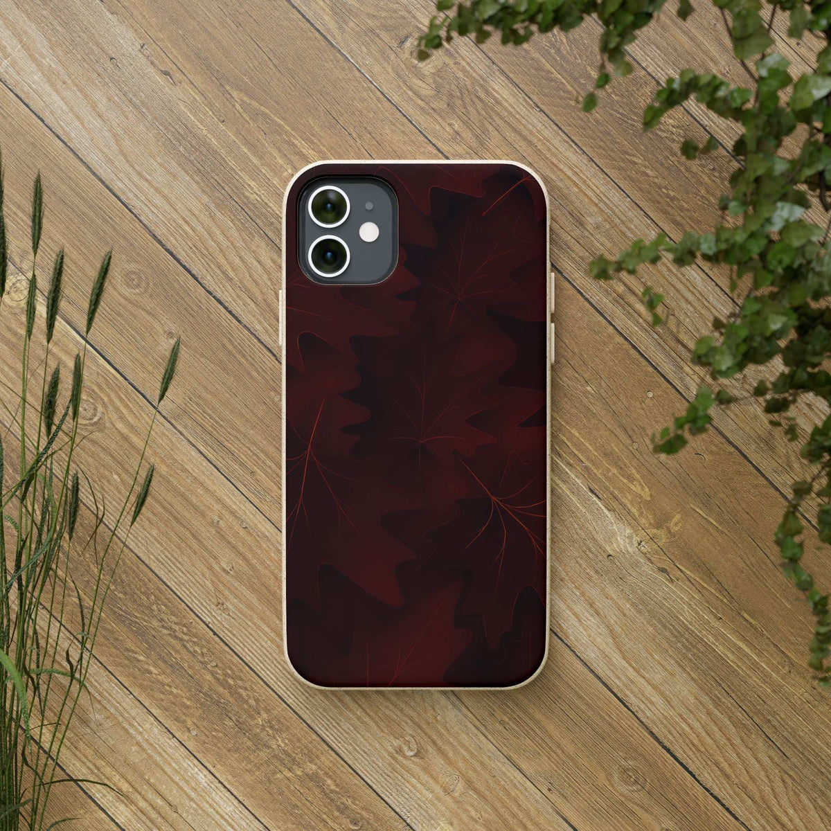 Maroon leaf-pattern phone case on a phone with camera cutout