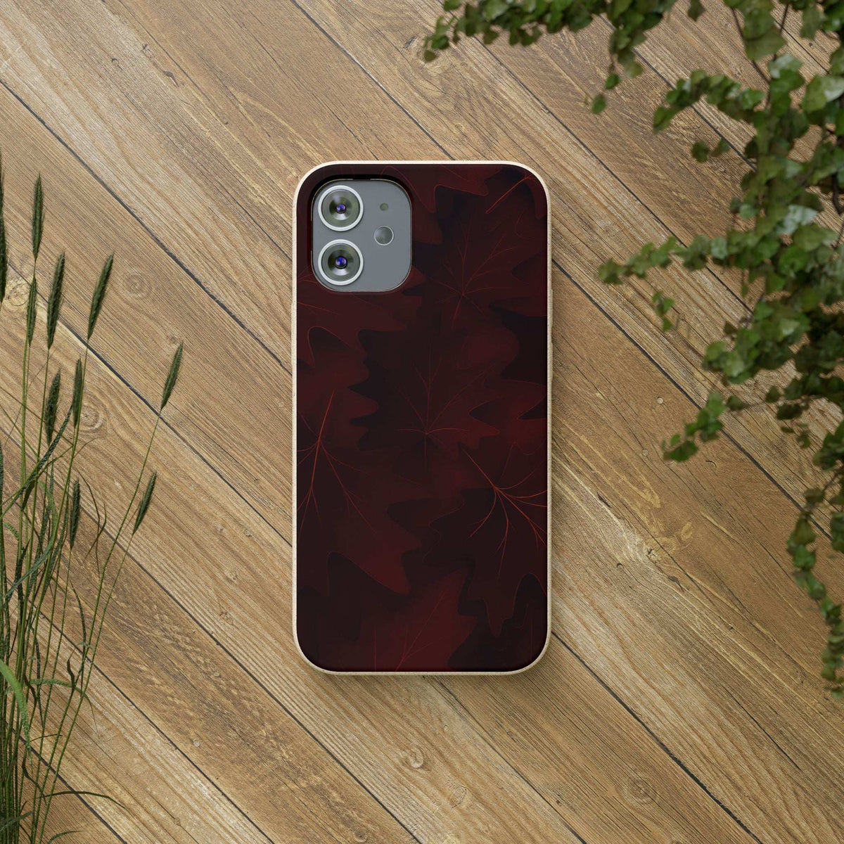 Leaf-pattern phone case on phone in dark maroon with red leaf design