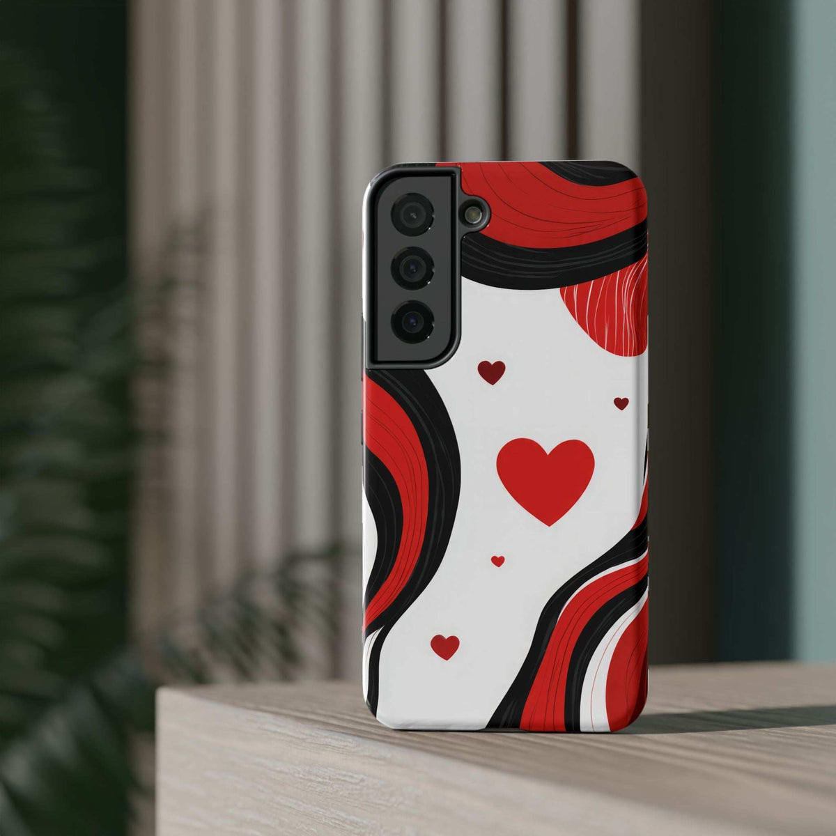 Red, black, and white swirl heart phone case standing upright with camera cutouts