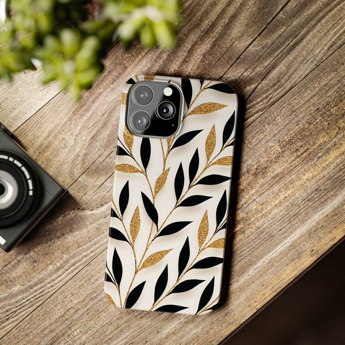 White leaf-pattern phone case with black botanical shapes and gold glitter, rear cameras