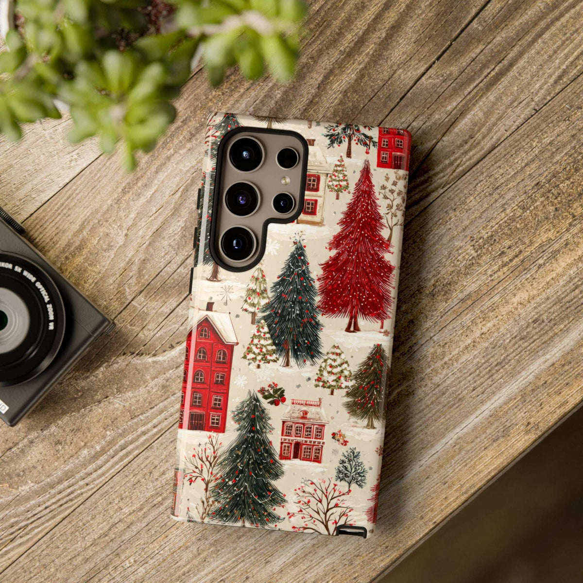 Phone case with winter village artwork, red houses and evergreen trees, camera openings