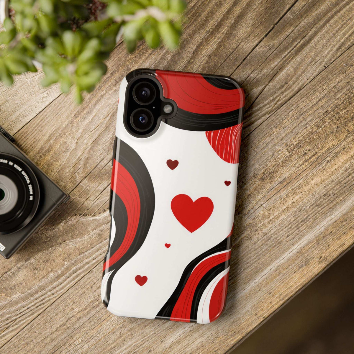 Phone case resting on wood surface with red hearts on white and black swirl pattern
