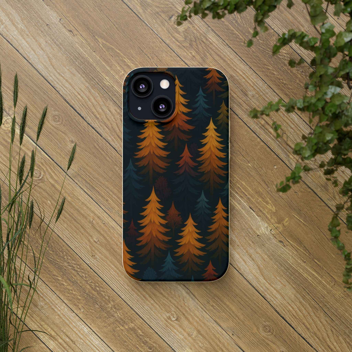 Biodegradable phone case with pine tree pattern in orange and teal on dark background; cameras visible