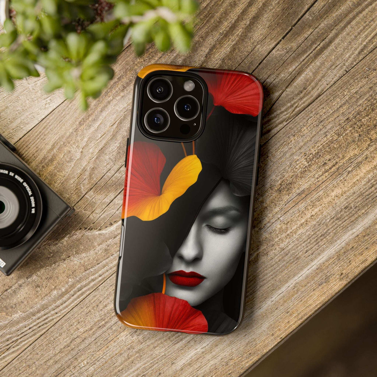 Glossy phone case with black design, red lips, and red/yellow flower woman-face artwork.