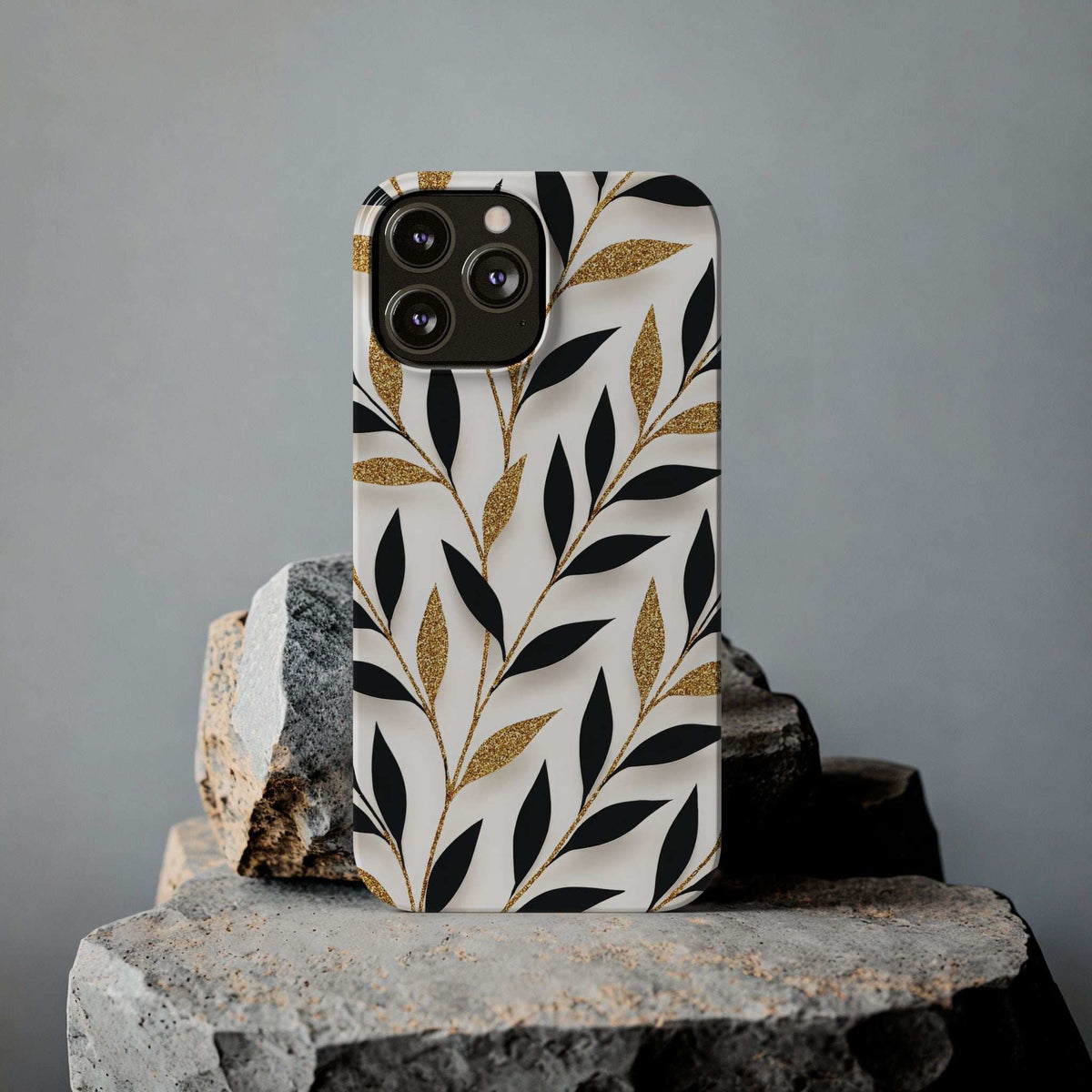 White botanical phone case with black leaves and gold glitter speckles, camera cutouts